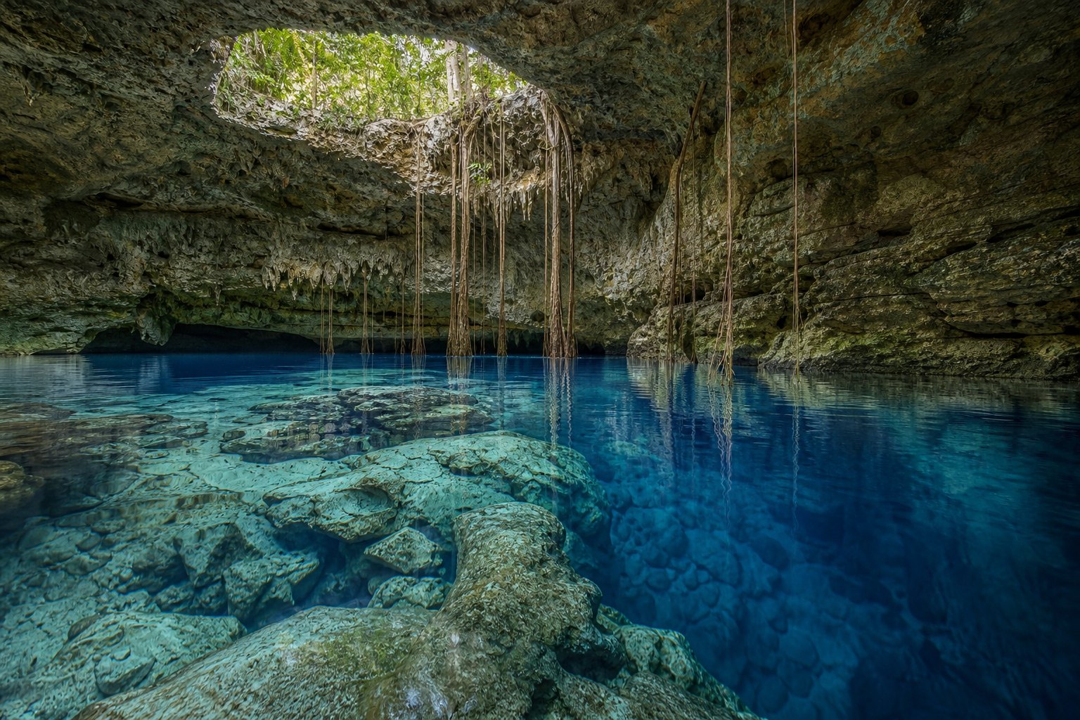 Agua azul transparente bajo una abertura natural de roca caliza