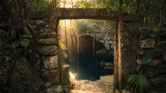 Umbral de piedra local frente a la entrada de un cenote al amanecer, imagen conceptual